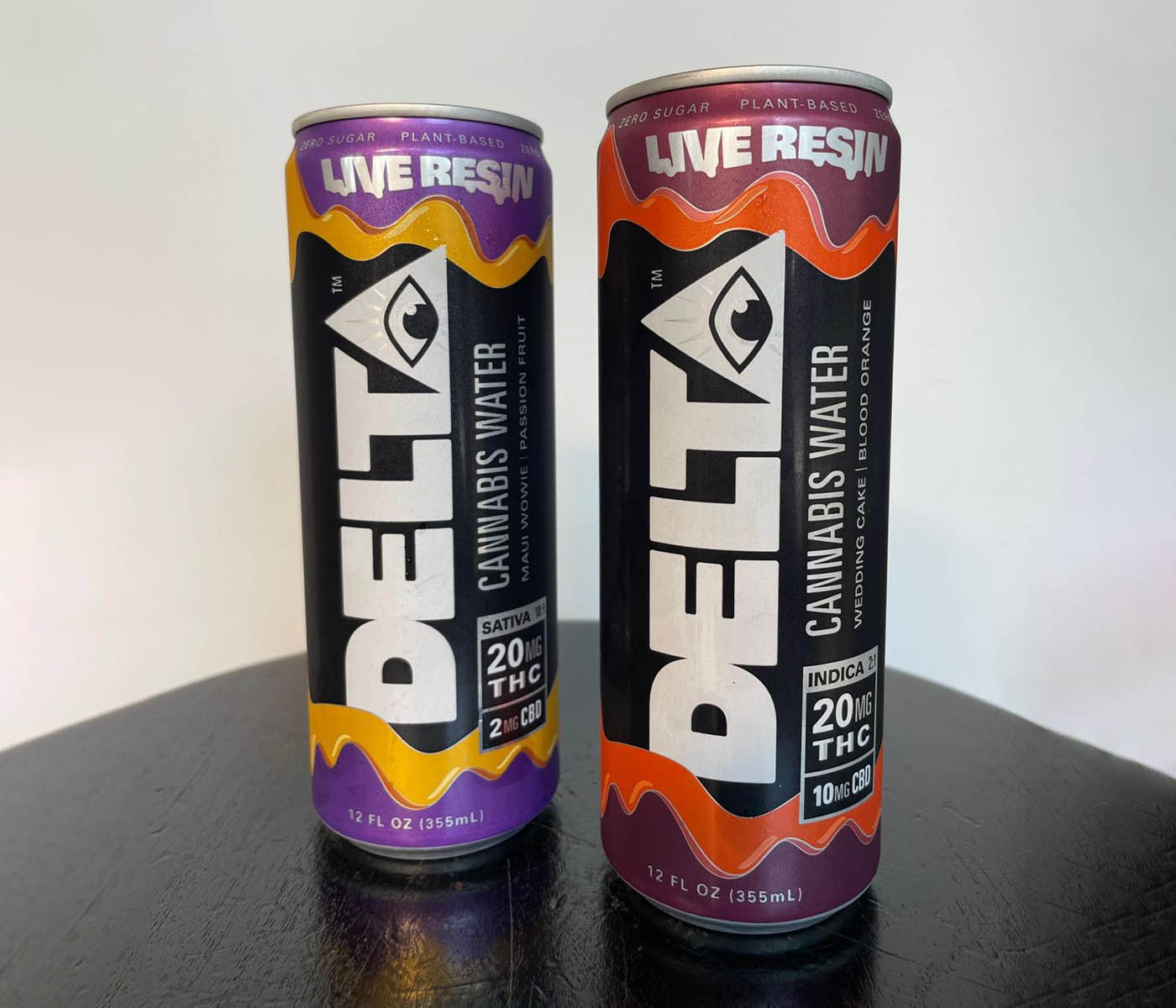 Two cans of Delta cannabis water side by side, Maui Wowie Passion Fruit flavor and Wedding Cake Blood Orange flavor